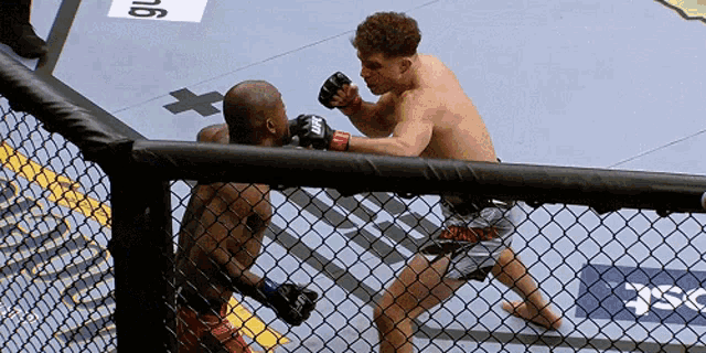 a man wearing a pair of ufc gloves is boxing another man