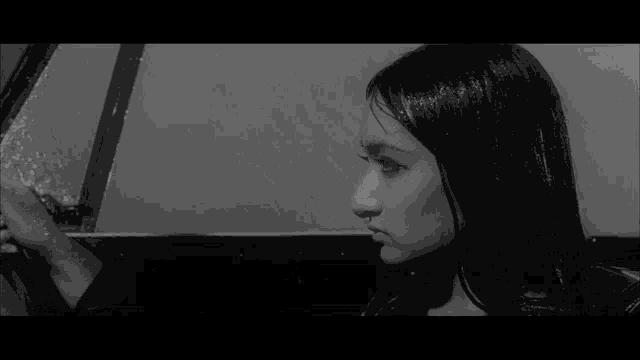 a black and white photo of a woman looking out of a car window