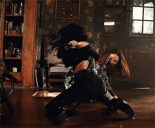 a man and a woman are dancing in a living room while a chair is in the background .