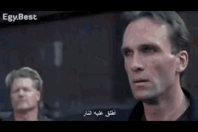 two men are standing next to each other and one of them has arabic writing on his face .