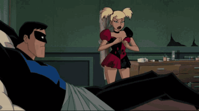 harley quinn is standing next to a man laying on a bed