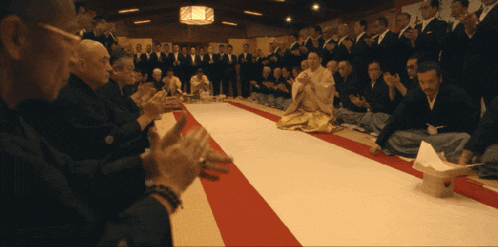 a group of men are sitting on the floor and clapping their hands