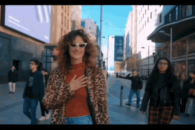 a woman wearing sunglasses and a leopard coat stands in front of a sign that says epm