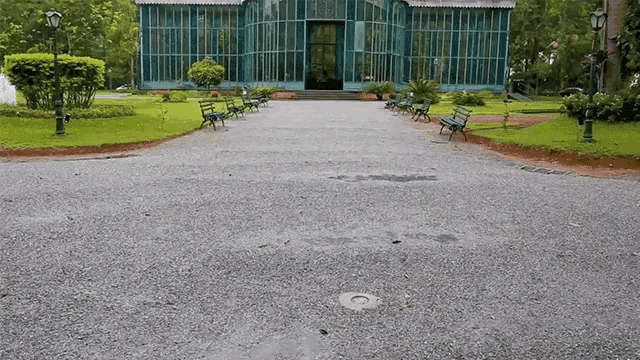 a gravel driveway leading to a greenhouse with green benches