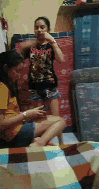 a girl wearing a shirt that says slipknot is sitting on a bed