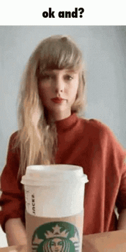 taylor swift is holding a starbucks coffee cup in her hand .