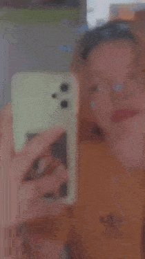 a girl is taking a selfie in front of a mirror with a butterfly on her face .