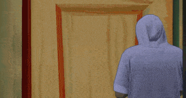 a man in a hooded shirt stands in front of a door