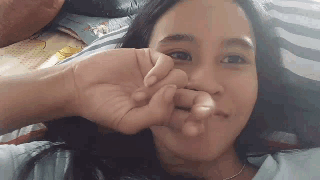 a young girl is laying on a bed with her hand on her face .