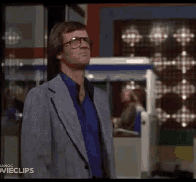 a man wearing glasses and a suit is standing in front of a machine .