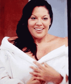 a woman in a white robe is smiling and looking at the camera