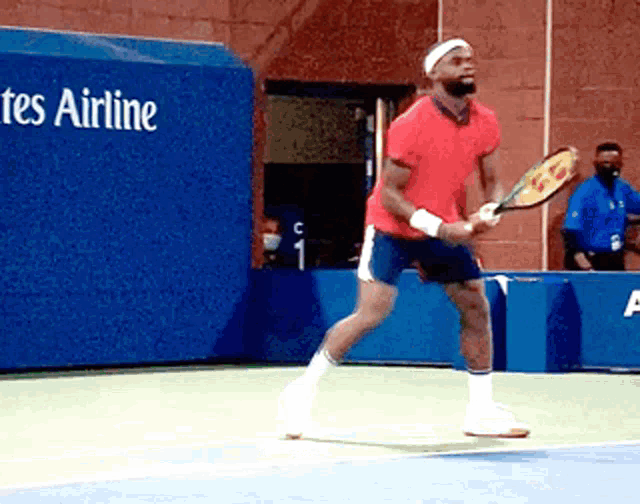 a man in a red shirt is holding a tennis racquet on a tennis court in front of a tes airline sign