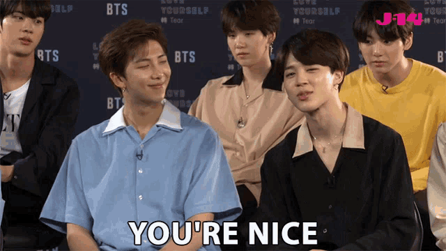 a group of boys are sitting in front of a sign that says ' bts ' on it