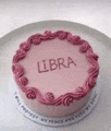 a pink cake with the word libra on it is on a plate .