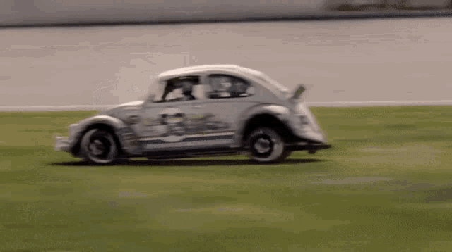 a white beetle is driving down a grassy road