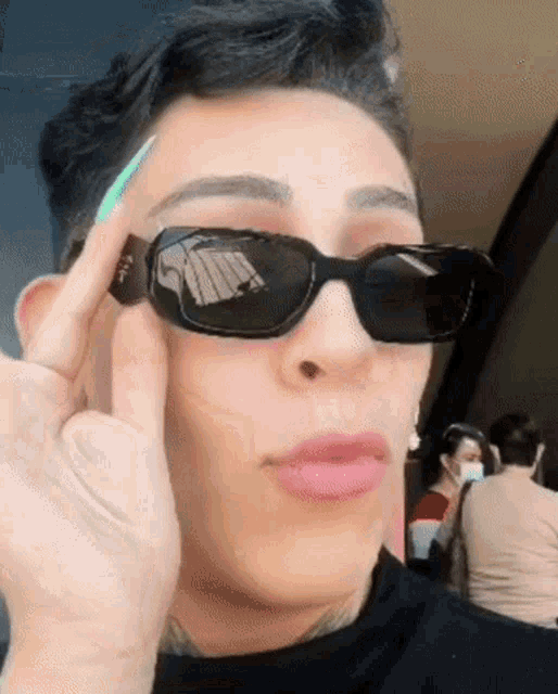 a close up of a person wearing sunglasses and making a funny face .