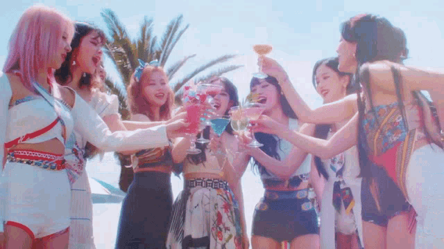 a group of girls are standing next to each other holding glasses of wine .