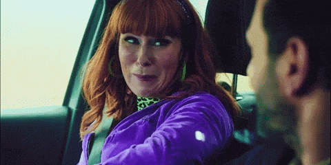 a woman in a purple jacket is sitting in the back seat of a car with a man .