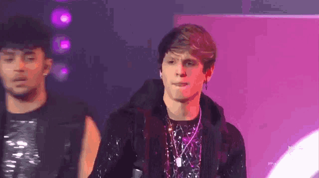 a young man is standing on a stage with a microphone in his hand