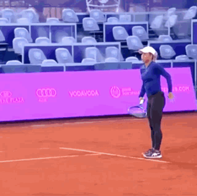 a woman is holding a tennis racquet in front of a purple wall that says virgin