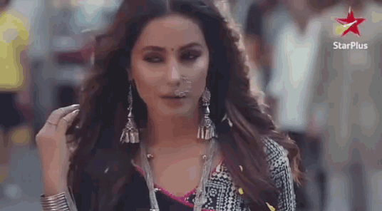 a woman wearing earrings and a nose ring is standing on a street .
