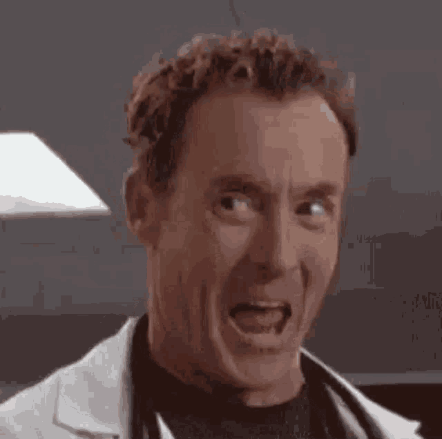 a man is smiling with his eyes closed and wearing a lab coat .
