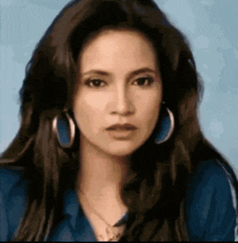 a close up of a woman wearing hoop earrings and a necklace