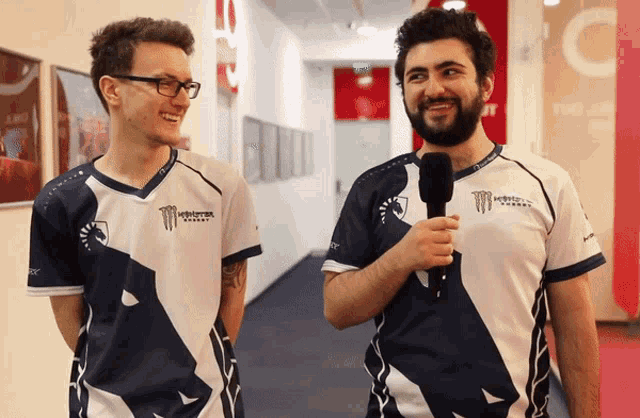 two men wearing monster energy shirts are standing next to each other in a hallway