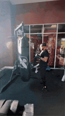 a man wearing boxing gloves is hitting a punching bag that says venum on it