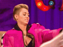 a woman in a pink jacket is sitting in front of a purple background