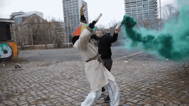 a man in a white coat is holding a green smoke bomb while another man holds an umbrella