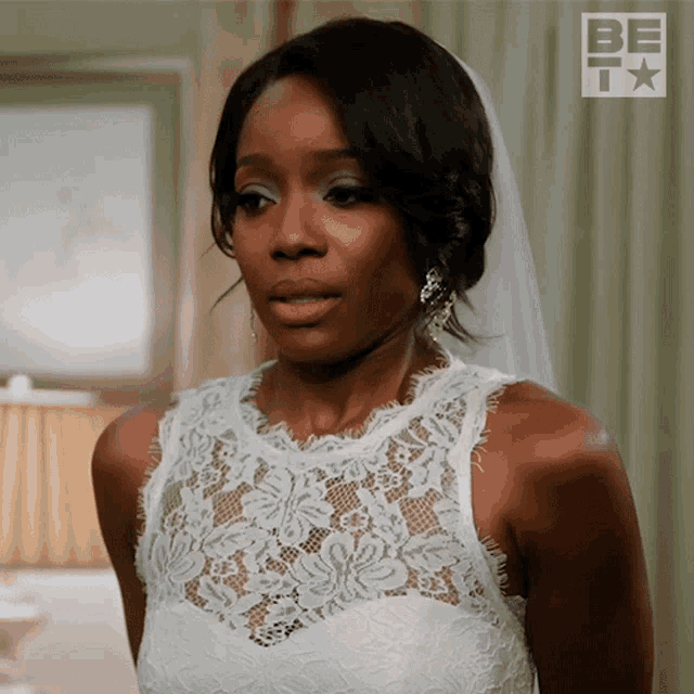 a woman in a wedding dress is standing in front of a sign that says be tv