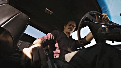 a man is sitting in a car with a gun in his hand