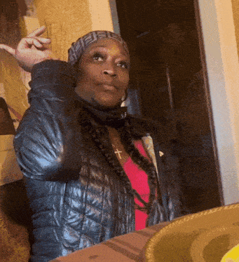 a woman wearing a black jacket and a pink shirt has a cross necklace