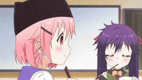 a girl with pink hair is holding chopsticks next to a girl with purple hair .