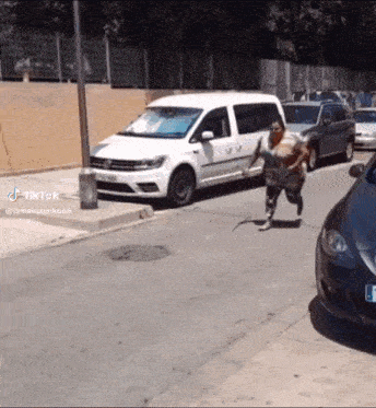 a woman is running down a street next to a white van