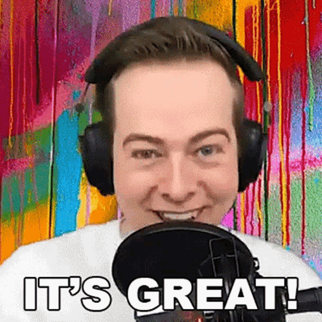 a man wearing headphones is talking into a microphone and smiling .