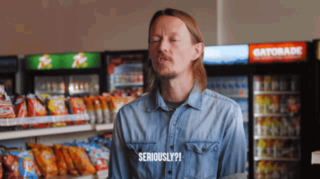 a man in a denim shirt says seriously in front of a gatorade cooler