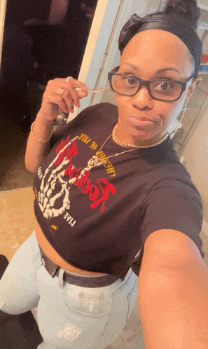 a woman taking a selfie wearing a black crop top that says ' king of the hill ' on it