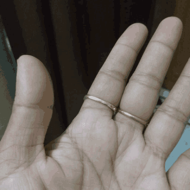 a close up of a person 's hand with two rings on