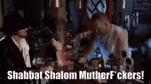 two men are sitting at a bar with a sign that says shabbat shalom