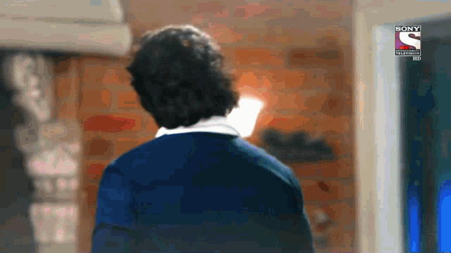 a man is standing in front of a wall with a sony logo on the bottom
