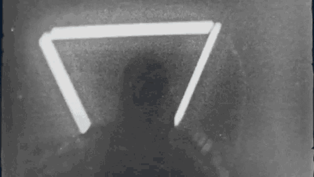 a black and white photo of a person in a hoodie holding a light saber .