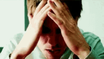 a man covering his face with his hands while looking at something