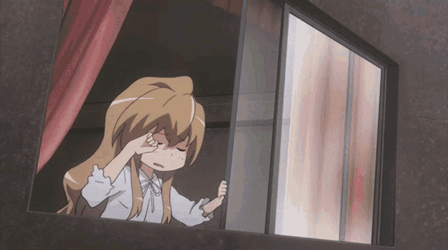 a girl is looking out of a window with a red curtain