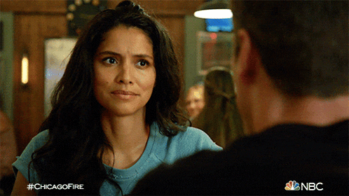 a woman in a blue shirt is looking at a man in a black shirt with nbc written on the bottom right