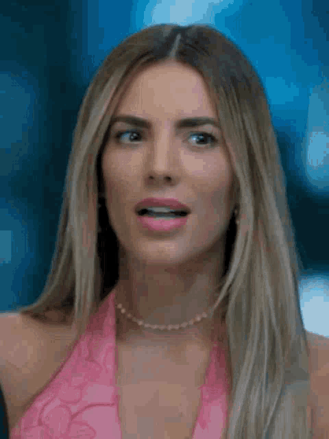 the woman is wearing a pink top and a pearl necklace .