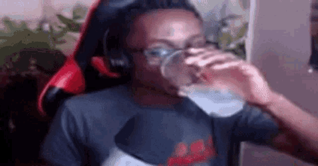 a man wearing headphones is drinking a glass of water .