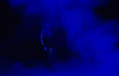 a man is standing in a dark room with blue lights