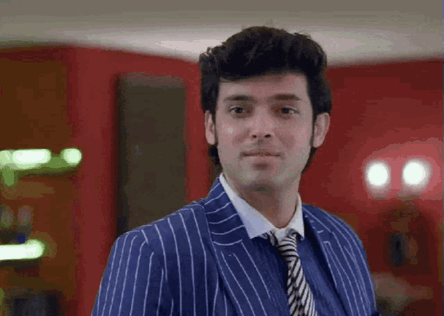 a man wearing a blue striped suit and tie looks at the camera